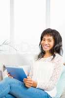Smiling woman using her tablet on couch