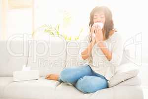 Pretty woman sneezing on couch