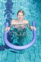 Fit woman doing aqua aerobics with foam rollers