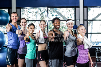 Smiling fitness class posing together with thumbs up