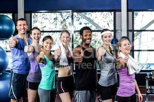 Smiling fitness class posing together with thumbs up