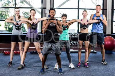 Class and instructor exercising with kettlebells