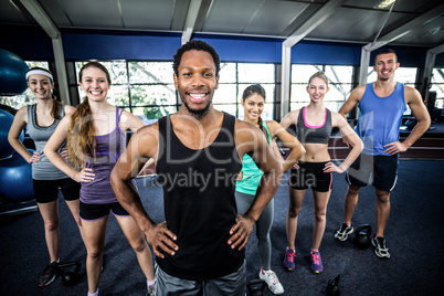 Smiling fitness class posing together with hands on hips