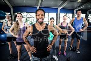 Smiling fitness class posing together with hands on hips