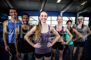 Smiling fitness class posing together with hands on hips