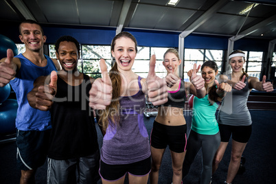 Smiling fitness class posing together with thumbs up