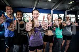 Smiling fitness class posing together with thumbs up