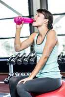 Thirsty woman drinking water on exercise ball