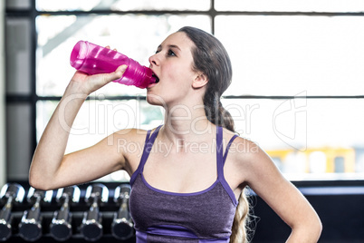 Thirsty woman drinking water on exercise ball