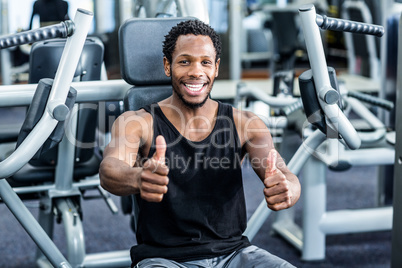 Smiling man with thumbs up using exercise machine