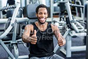 Smiling man with thumbs up using exercise machine