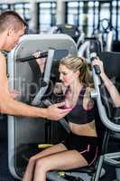Trainer motivating woman while using exercise machine