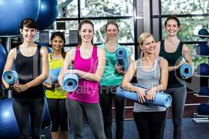 Fit smiling group holding sports mats