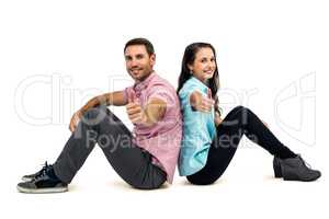 Smiling couple sitting showing thumbs up