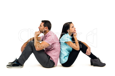 Thoughtful couple sitting on the floor back to back with hands o