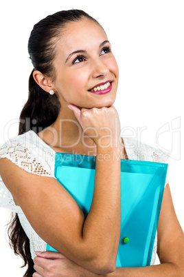 Smiling thoughtful woman holding plastic folder with fist on chi