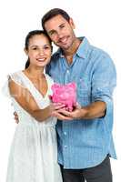 Smiling couple holding piggybank