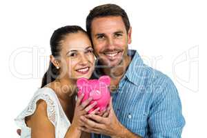 Smiling couple holding pink piggybank