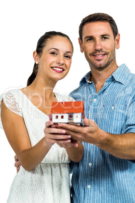 Confident couple holding house model