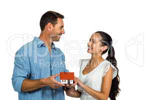 Face to face couple holding house model