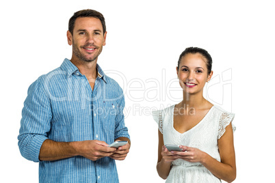 Smiling couple using smartphones and looking at camera