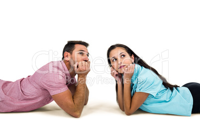 Thoughtful couple laying on floor looking away