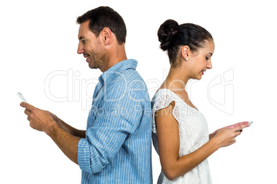 Couple standing back to back using smartphones