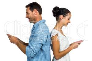 Couple standing back to back using smartphones