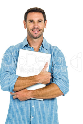Young man holding laptop looking at the camera
