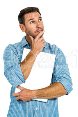 Thoughtful man with hand on chin holding laptop