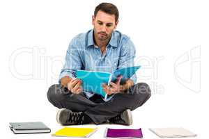 Man sitting on the floor reading notepad
