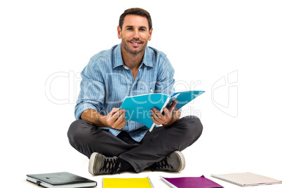 Portrait of man sitting on the floor holding notepad