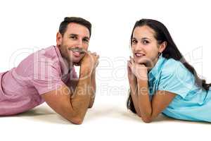 Smiling couple laying on the floor face to face looking at the c