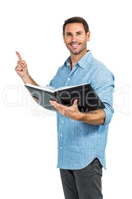 Smiling man holding a book and pointing up