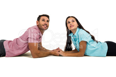 Couple laying on the floor face to face holding hands and lookin