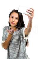 Young woman blowing kiss while taking selfie