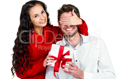 Young woman covering eyes of partner holding gift