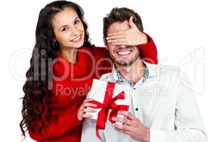 Young woman covering eyes of partner holding gift
