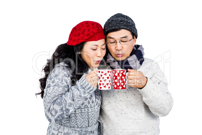 Happy couple blowing on cups