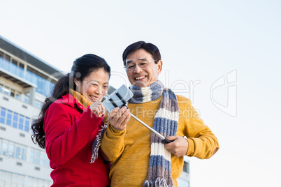 Older asian couple on balcony taking selfie