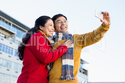 Older asian couple on balcony taking selfie