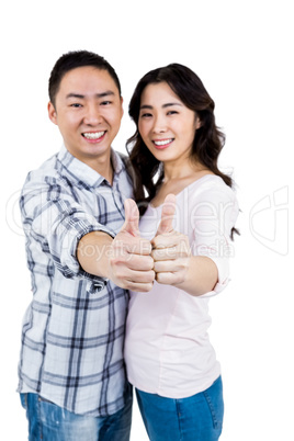 Happy couple showing thumbs up against white background