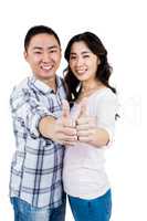 Happy couple showing thumbs up against white background