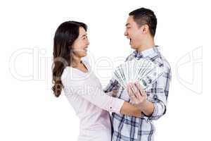 Cheerful happy couple holding money while standing