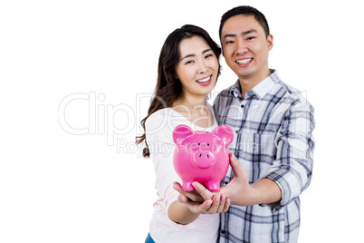 Portrait of cheerful couple holding piggy bank