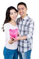 Portrait of happy smiling couple holding piggy bank