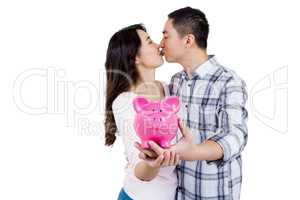 Couple kissing while holding piggy bank