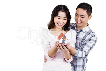 Happy couple holding a model house