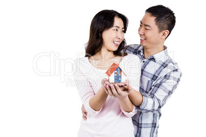 Cheerful couple holding a model house