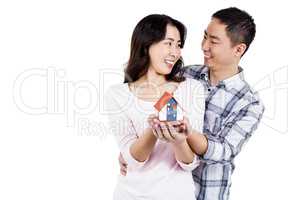 Cheerful couple holding a model house